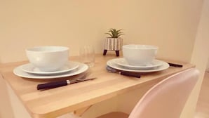 A dining table with two white bowls, a glass, and a knife on a wooden table. - London Chelsea, Big 2 People Studio Apartment (London)