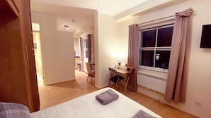 A hotel room with a bed, a desk, and a window. - London Chelsea, Big 2 People Studio Apartment (London)