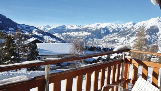 A wooden balcony with a snow-covered mountain view.