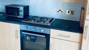Eine Küche mit Holzausstattung, einer Mikrowelle, einem Gasherd und einem Backofen.