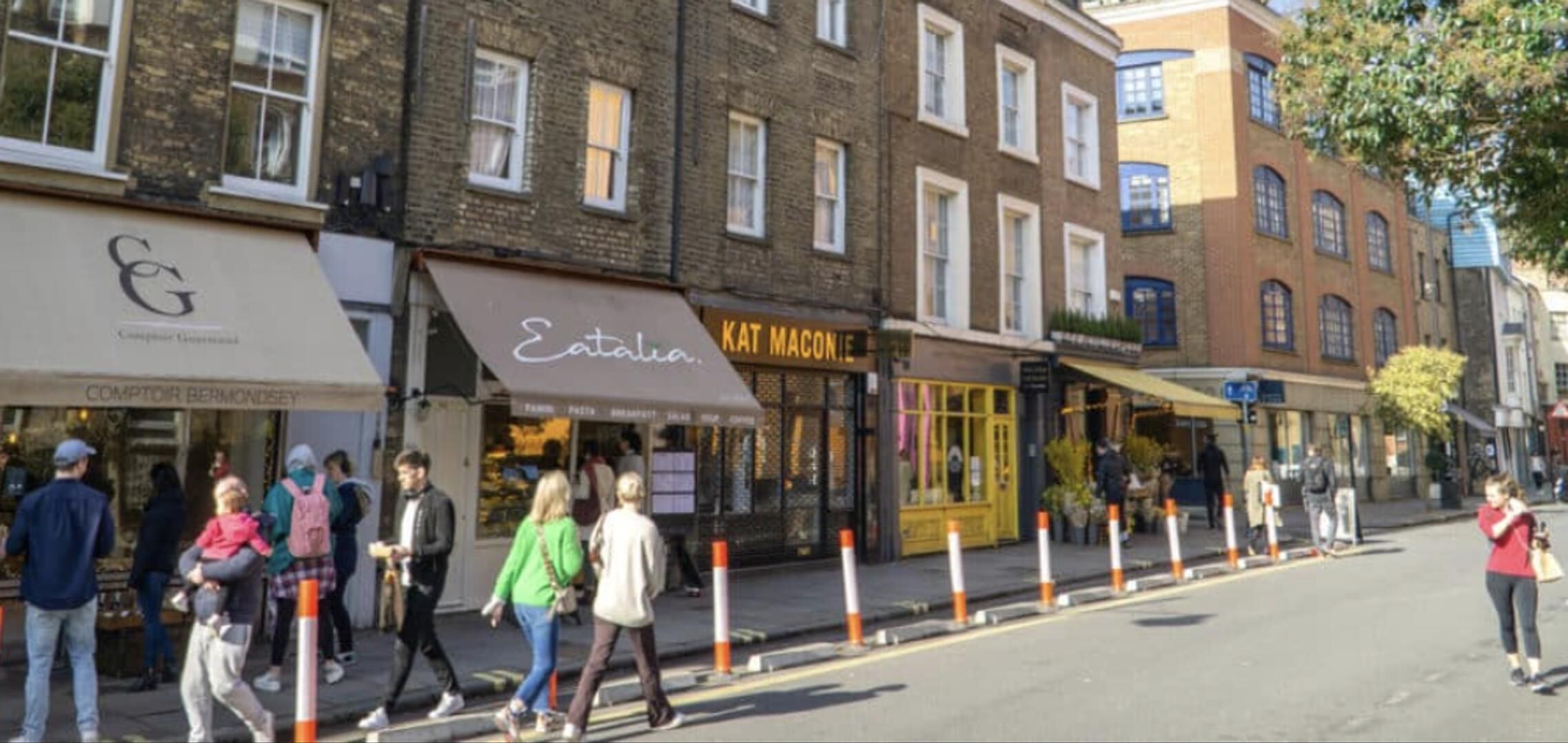 A street with pedestrians and storefronts, including a visible restaurant named 'Kat Macionie'.