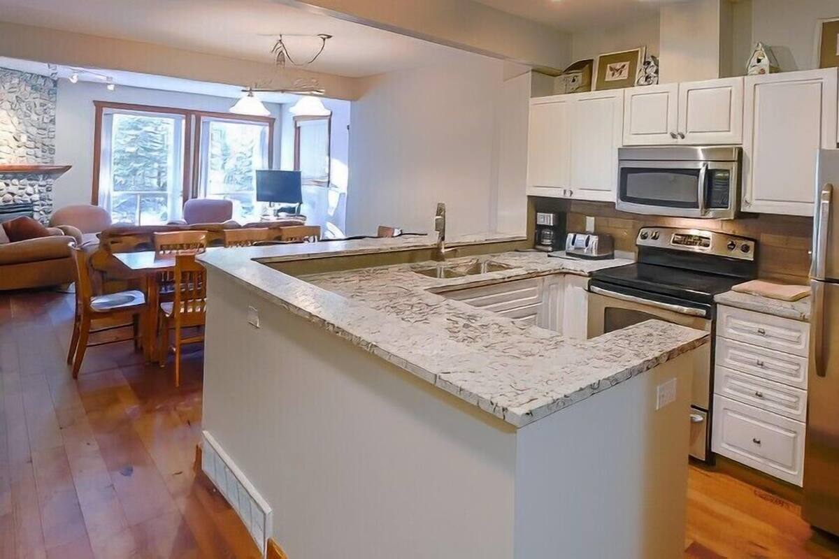 A kitchen with white cabinets, a stainless steel refrigerator, a microwave, and a stove.
