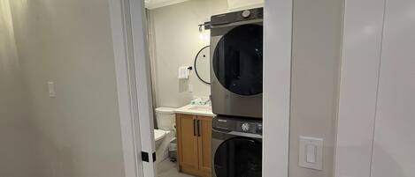 A laundry room with a washing machine, dryer, and a small countertop with a sink.