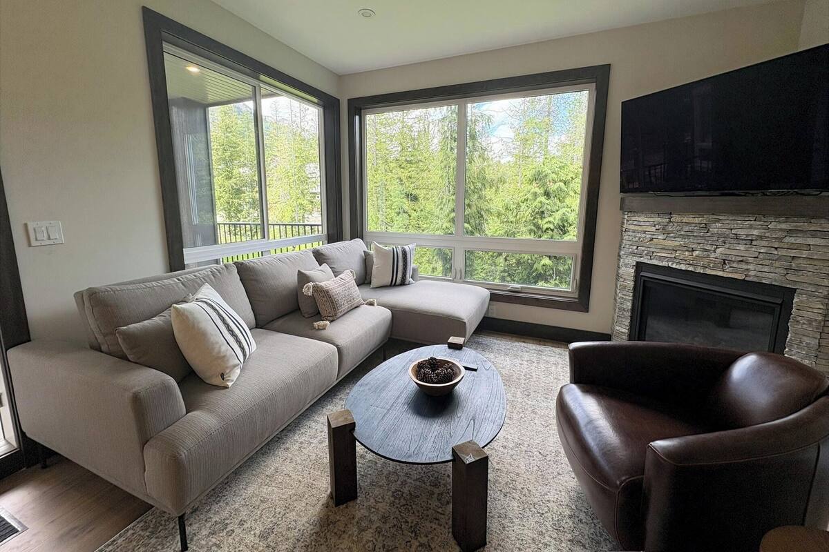A living room with a sofa, armchair, coffee table, and a fireplace.