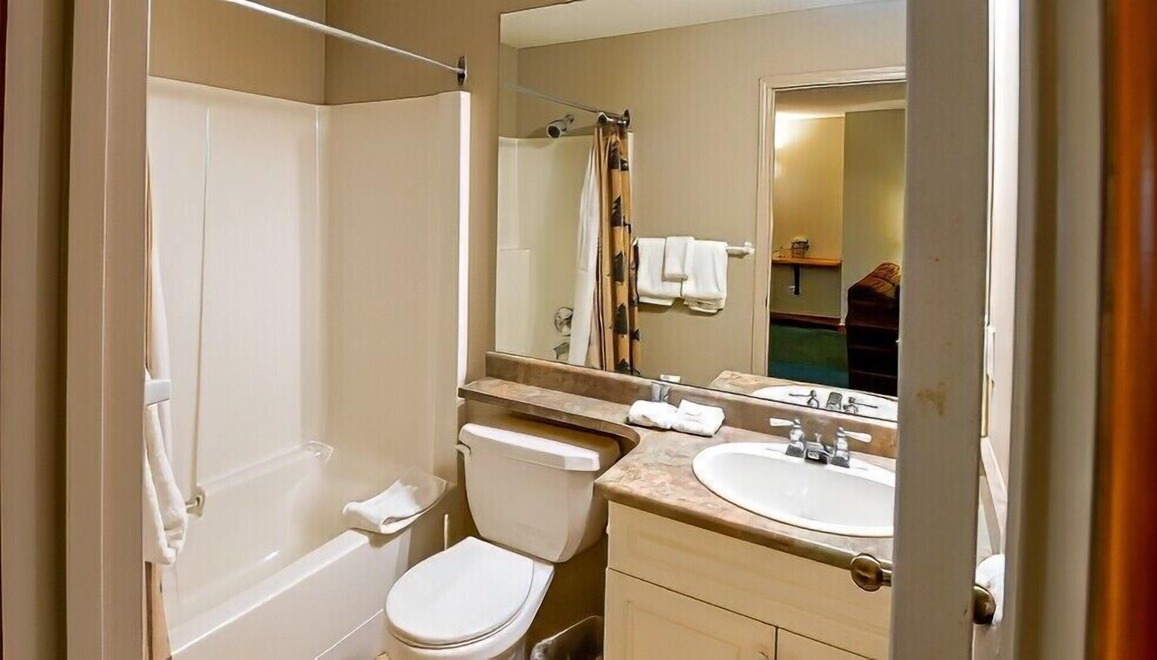 A standard hotel bathroom with a bathtub, toilet, sink, and a large mirror.