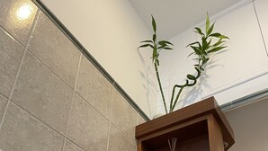 Une salle de bain avec une étagère en bois où sont posés des serviettes, une plante en bambou et des objets décoratifs.