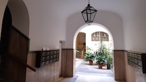Un couloir voûté orné d’une lanterne suspendue, de plantes en pot et d’un meuble de rangement en métal.
