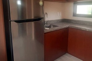 A kitchen with a stainless steel refrigerator, a granite countertop, and wooden cabinets.