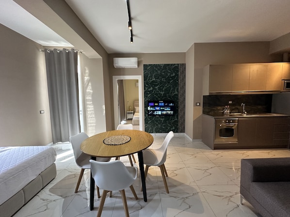 Relax in this stylish living area with a dining table for two, sofa, and TV.
