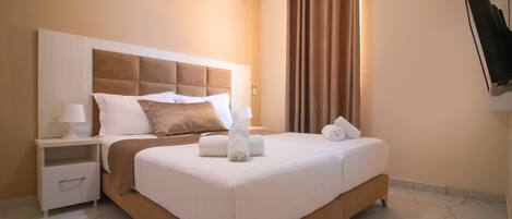 Une chambre d’hôtel avec un grand lit, une table de chevet, un climatiseur fixé au mur et une fenêtre avec des rideaux.