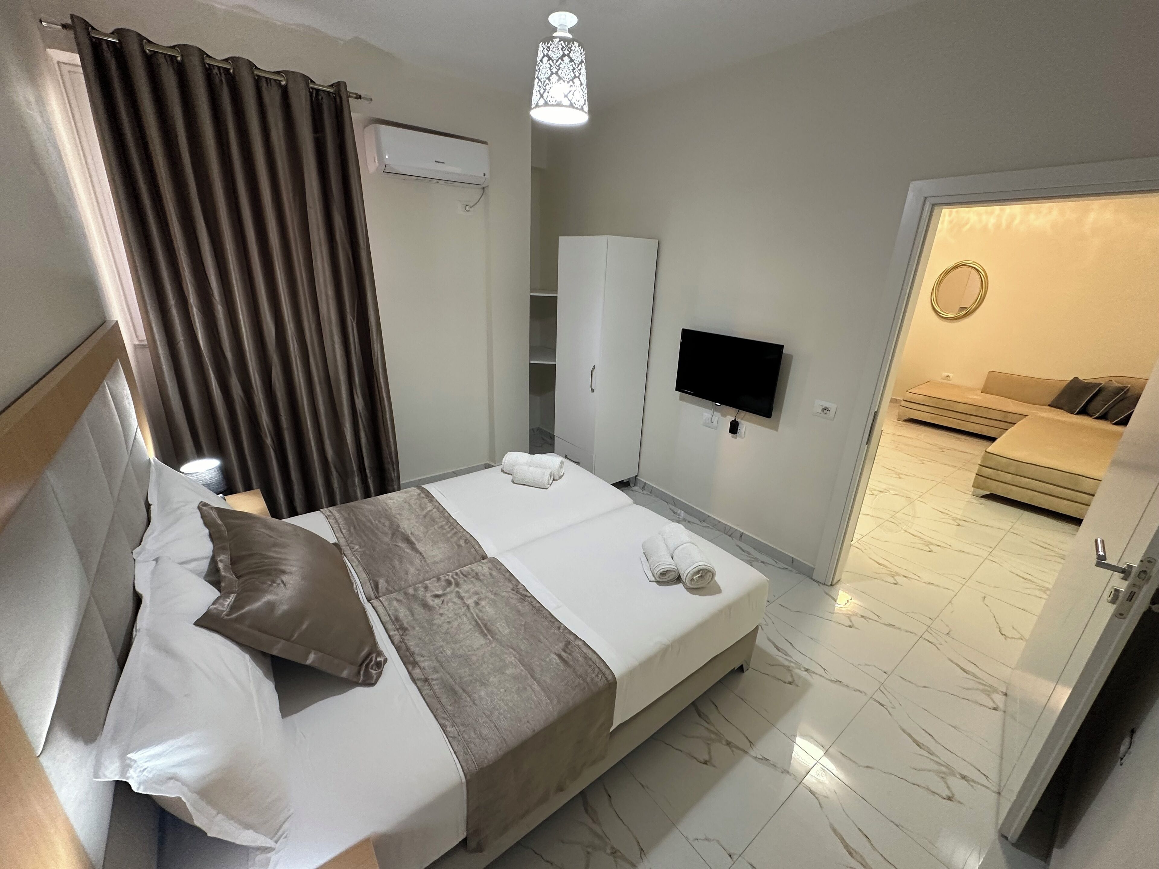 Hotelkamer met een bed, een televisie, een airconditioner, een kledingkast en een badkamer zichtbaar door een geopende deur.