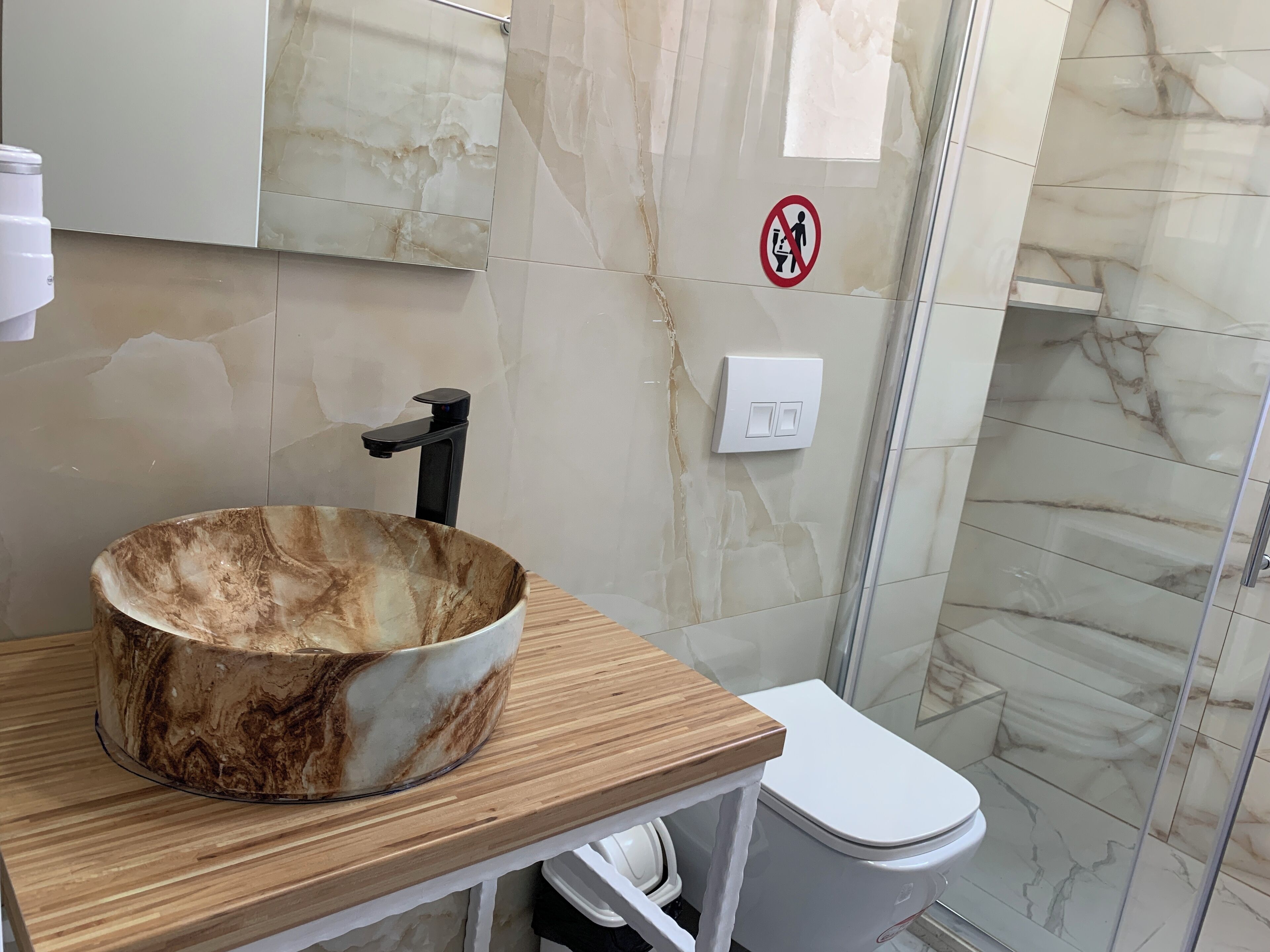 A bathroom with a marble vanity, a toilet, and a shower area.