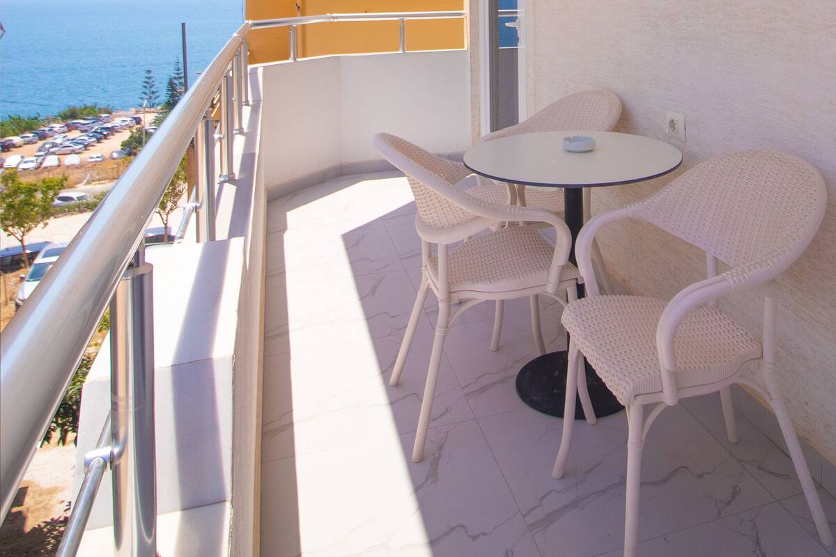 Un balcon avec une table et des chaises, offrant une vue sur la côte.