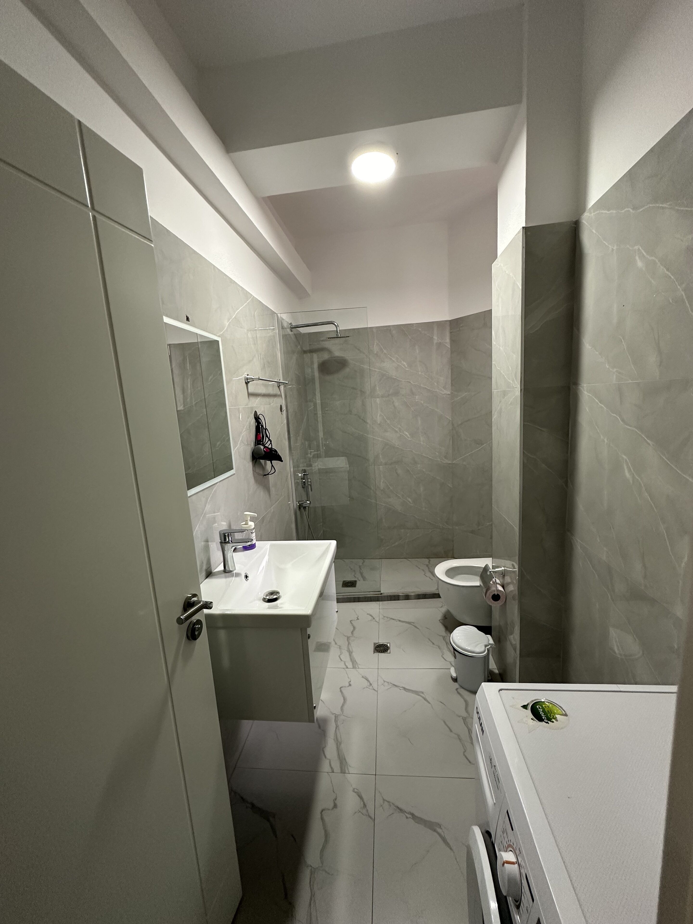 A modern bathroom with a glass shower enclosure, a white sink, a toilet, and a bathtub.
