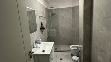 A modern bathroom with a glass shower enclosure, a white sink, a toilet, and a bathtub.