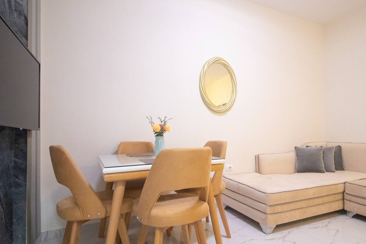 Un salon moderne comprenant un coin repas, un canapé et un miroir fixé au mur.
