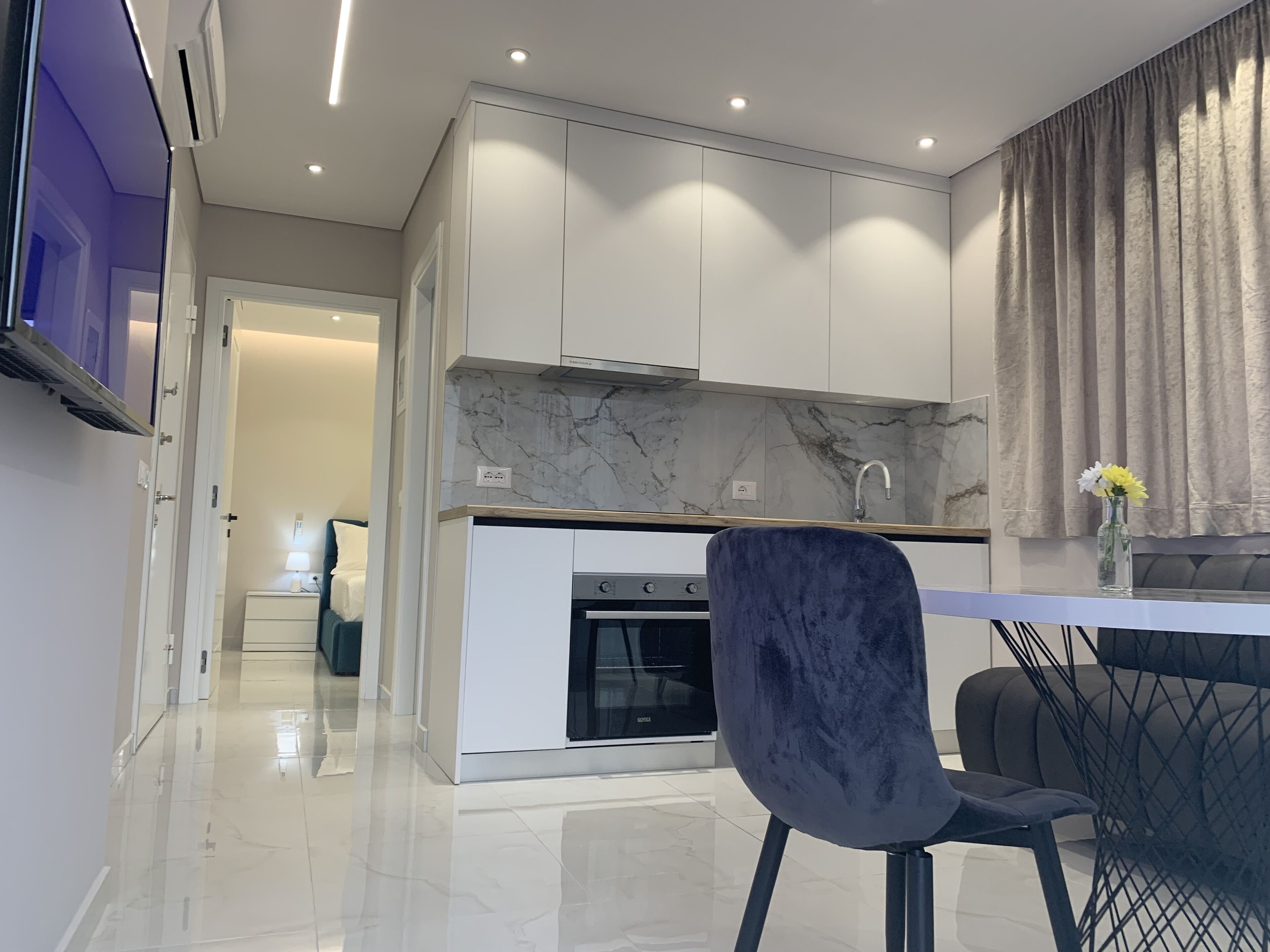 A modern kitchen with white cabinets, a marble backsplash, and a built-in oven.
