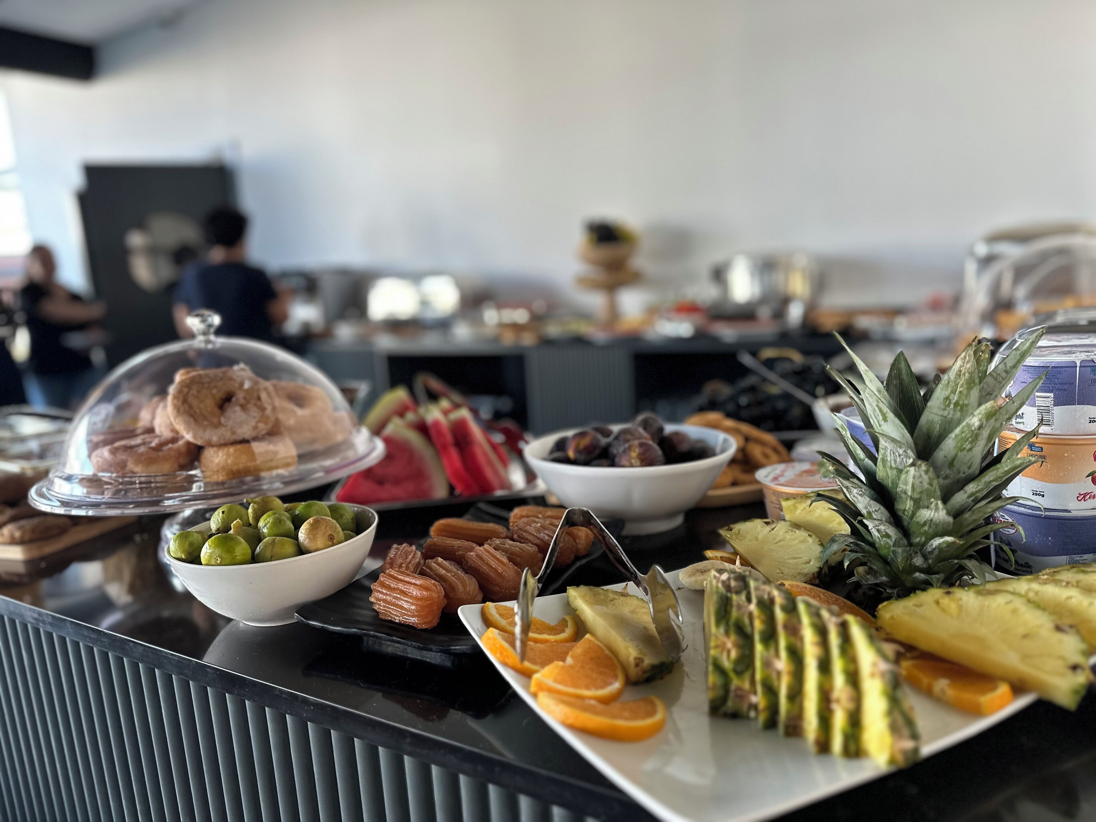 A buffet with various food items including pastries, fruits, and vegetables.
