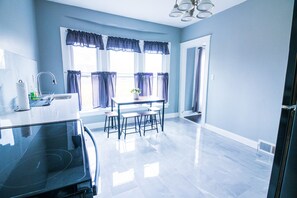 A modern kitchen with a black stove, a sink, and a window with purple curtains. - Cozy 1 bedroom Apartment Sleeps 4 (Niagara Falls)
