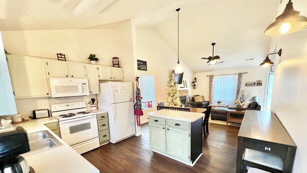 A modern kitchen with white cabinets, a central island, and a dining area with a dark countertop. - Cozy Cottage (Pigeon Forge)