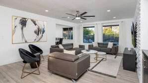 A modern living room with a sectional sofa, two armchairs, a coffee table, and a ceiling fan.