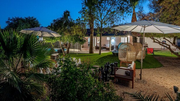 A well-lit outdoor area with umbrellas, a chess table, and a pool.