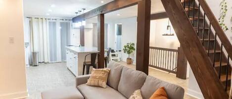 Una sala de estar moderna con un sofá, una mesa de centro y una escalera.