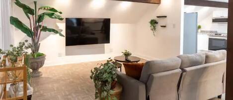 Una sala de estar moderna con un sofá, un televisor y plantas en macetas.