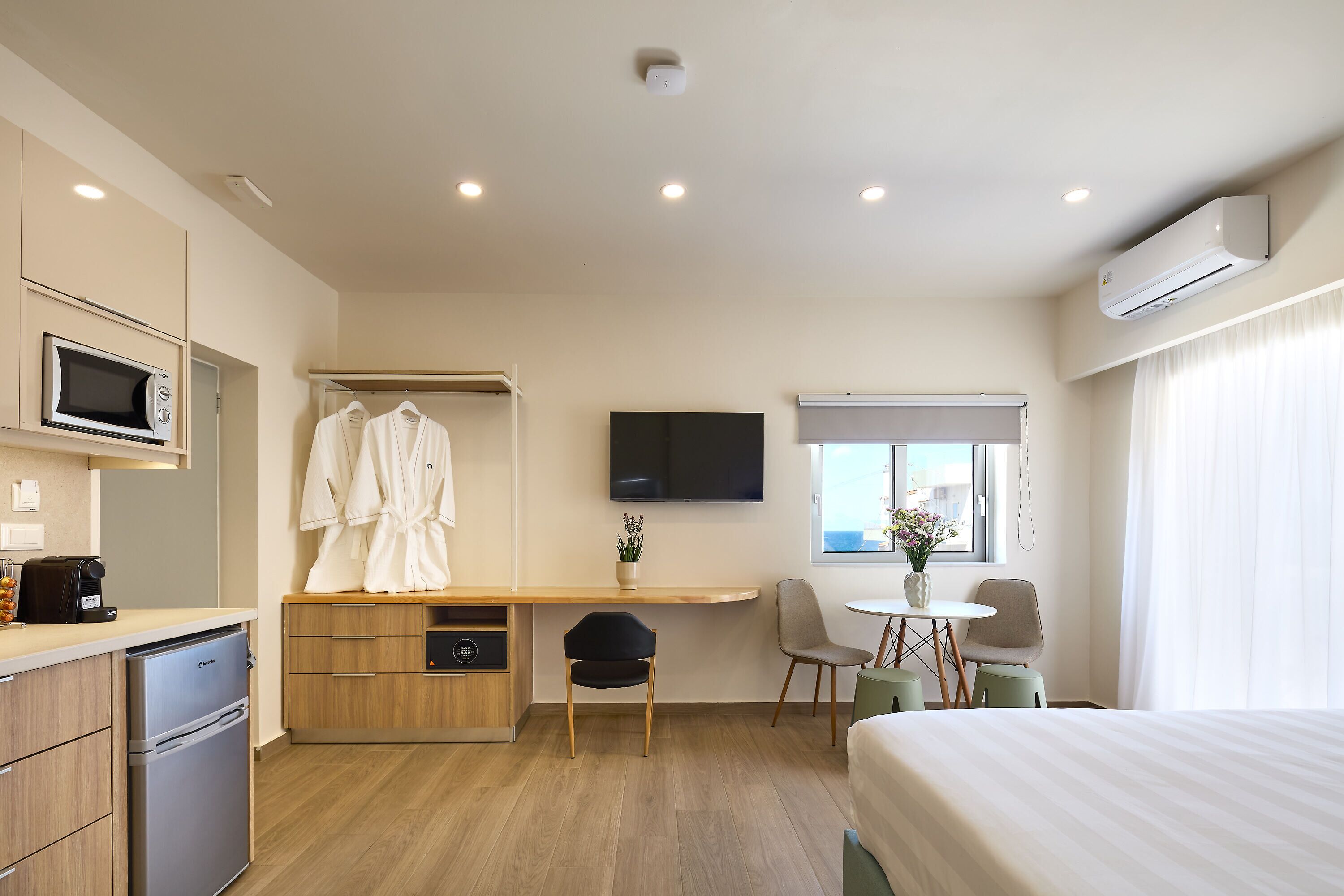 Ein Hotelzimmer mit einem Bett, einem Schreibtisch mit Stuhl, einer Mikrowelle, einem Kühlschrank und einem Fernseher.