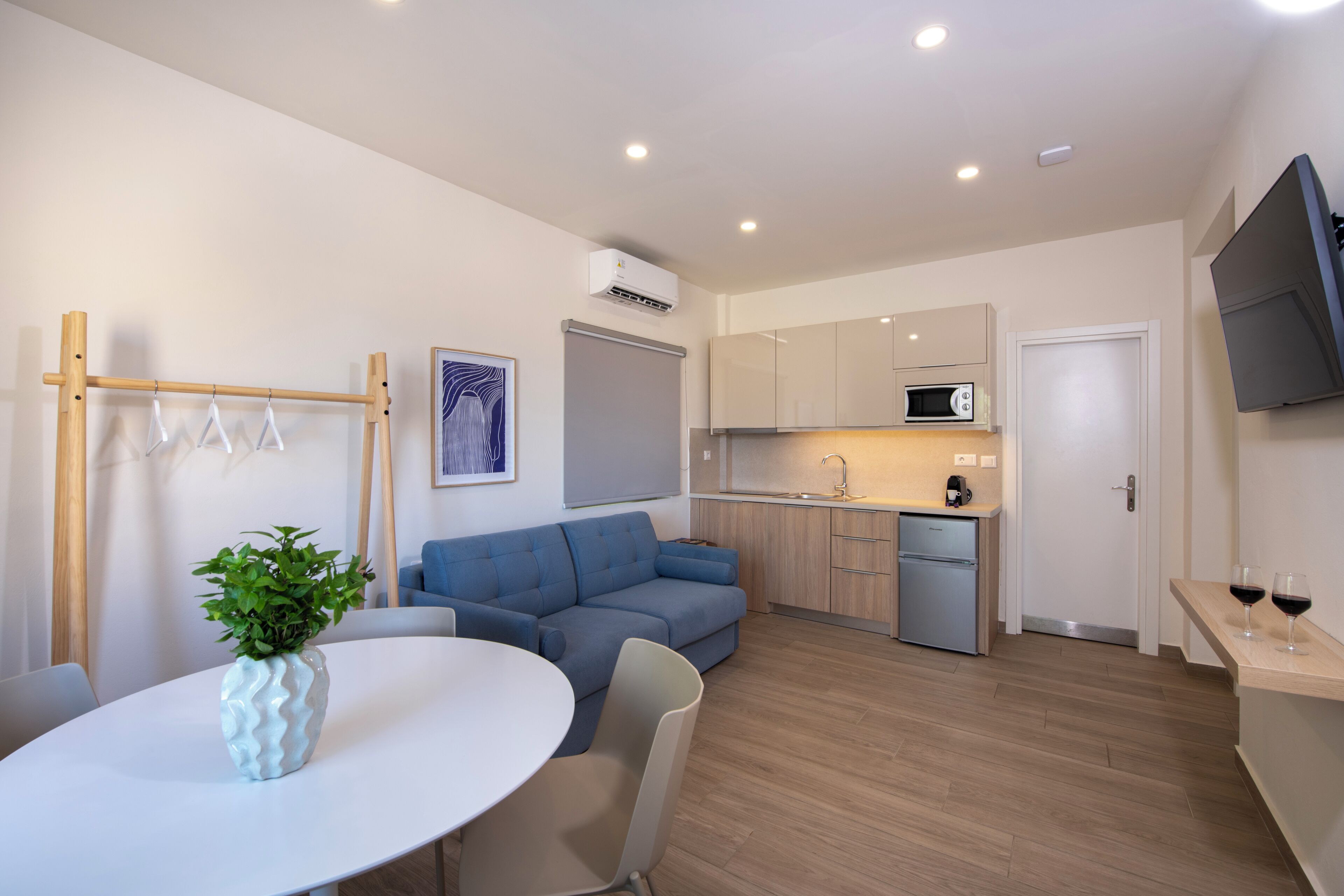 Um apartamento moderno com área de refeições, sofá, cozinha equipada com micro-ondas e televisão na parede.
