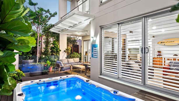 A modern outdoor pool area with a hot tub, seating, and a view of the interior through large glass doors. - Villa Marguerite - walking distance to the beach (Coolum Beach)