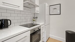 A modern kitchen with white cabinetry, a black kettle, and a framed plant on the wall. - NEW LISTING!!! South Kensington Style newly refurbished apartment (London)