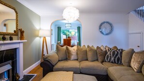 A living room with a fireplace, a sofa set, a clock, and a dining area visible through an archway. - Spacious 4-br Cambridge House, Free Parking (Cambridge)