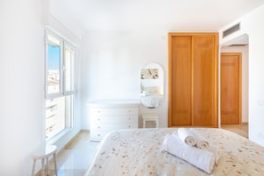 A bedroom with a bed, a dresser, a mirror, and a wardrobe.