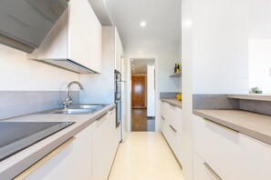A modern kitchen with a stainless steel sink, a built-in oven, and a countertop. - La Carihuela II | Stylish Coastal Apartment with Terrace, Pool & Beach (Torremolinos)