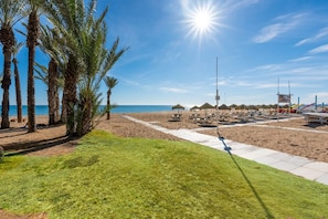 Une plage bordée de palmiers, avec des parasols et des chaises longues.