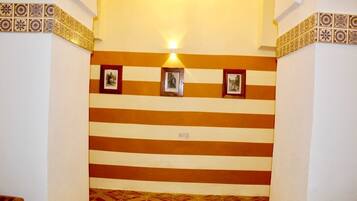 A hallway with striped walls, framed pictures, and patterned floor tiles.