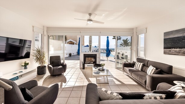 A modern living room with a flat-screen TV, sofas, a coffee table, and a fireplace. - Faros Beachfront Villa Larnaca (Larnaca)
