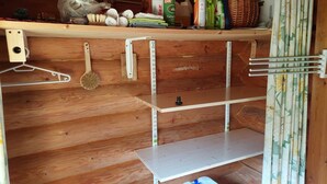 A wooden interior with shelves, a hanging broom, and a curtain.
