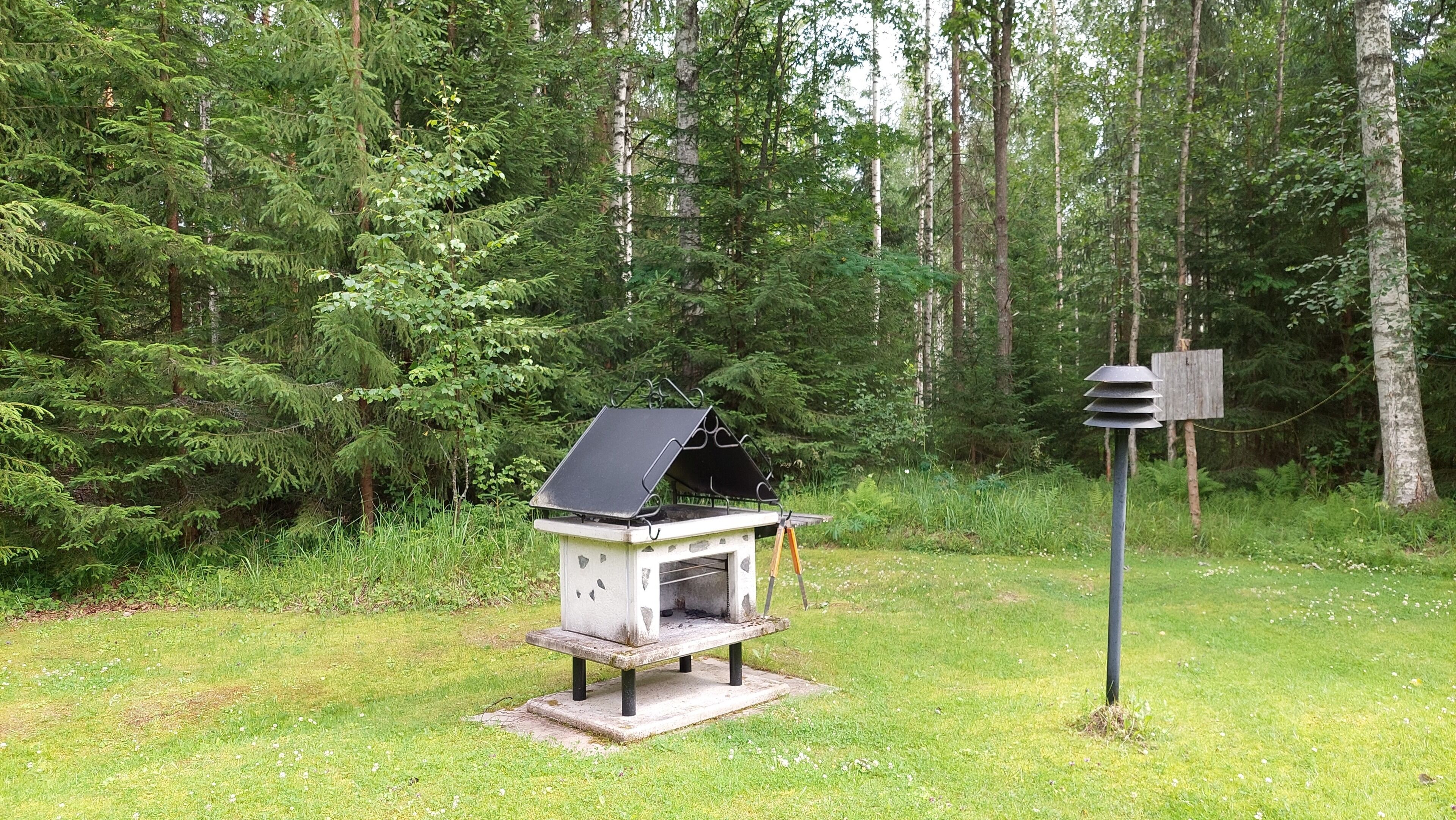 Un barbecue portable situé dans une zone boisée, avec un panneau indicateur à proximité.