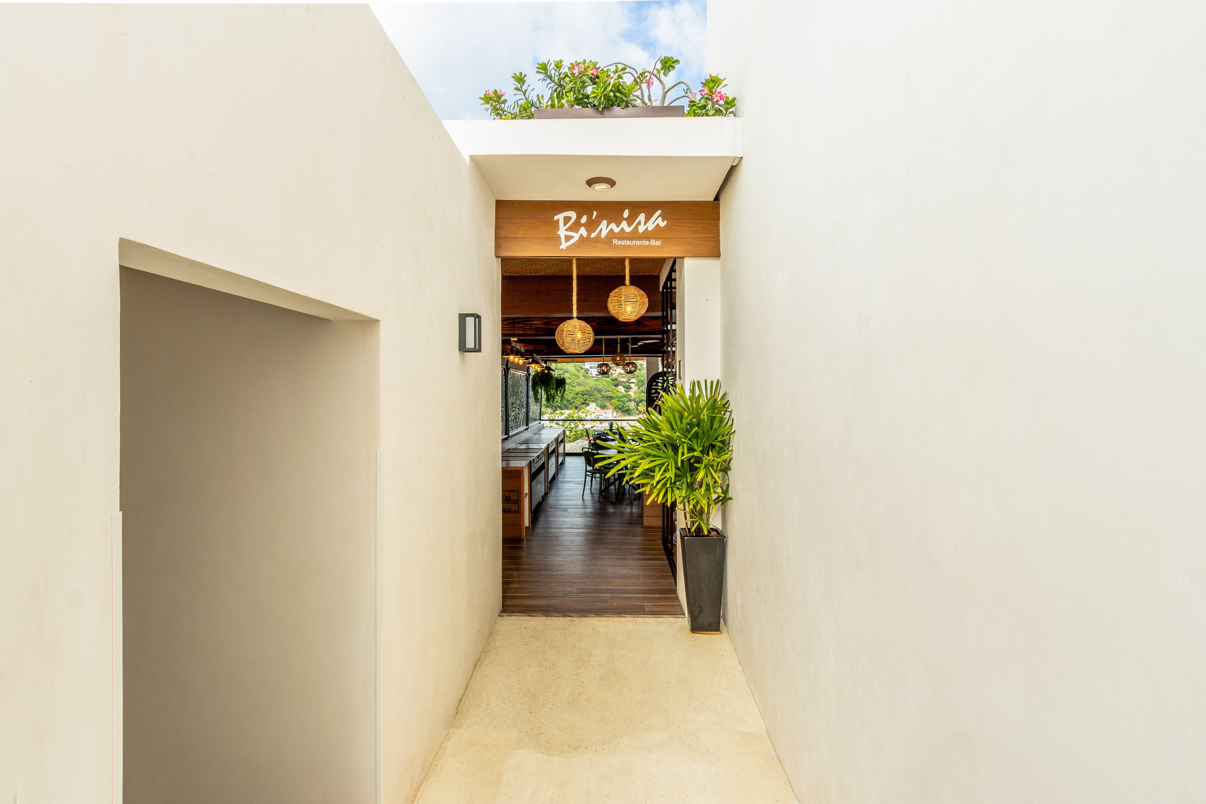 Un pasillo estrecho que conduce a un restaurante con un letrero de madera que dice "B'inisa Restaurant-Bar".