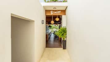 Un pasillo estrecho que conduce a un restaurante con un letrero de madera que dice "B'inisa Restaurant-Bar".