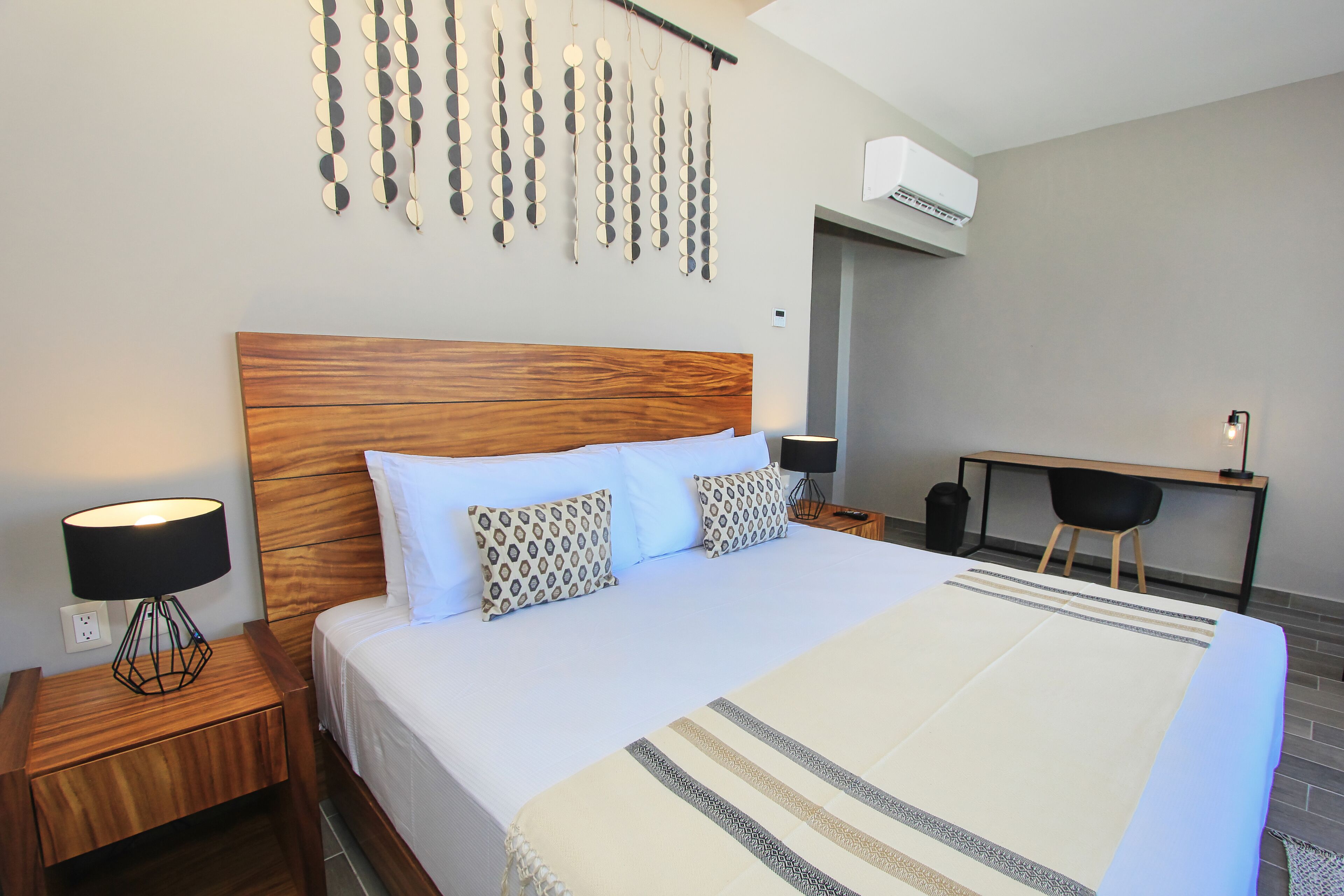 A neatly made bed with a wooden headboard, a bedside lamp, and patterned pillows.