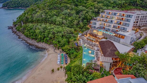 Un hotel con varios pisos, piscina y playa.