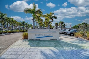 Naamplaatje voor Sarasota County Park, Sienna Beach, met een verharde looppad en geparkeerde auto's.