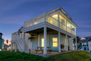 A two-story house with a balcony, a staircase, and a barbecue grill in the yard.