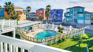 A residential area with colorful houses, a swimming pool, and a white fence. - Holiday Beach House by Avantstay Pool + Beach (Port Aransas)