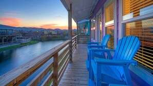 A wooden deck with blue Adirondack chairs overlooking a river and distant buildings. - Purple Pelican by Avantstay Waterfront Oasis (Port Aransas)