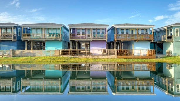 A row of modern waterfront homes with balconies, reflecting in the water. - Purple Pelican by Avantstay Waterfront Oasis (Port Aransas)