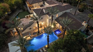 A large house with a swimming pool, multiple patios, and a well-maintained garden. - Luxe 7bdr Oasis w/ Pool, Putting Green, Game Room Villa Del Gallo by Avantstay (Indio)